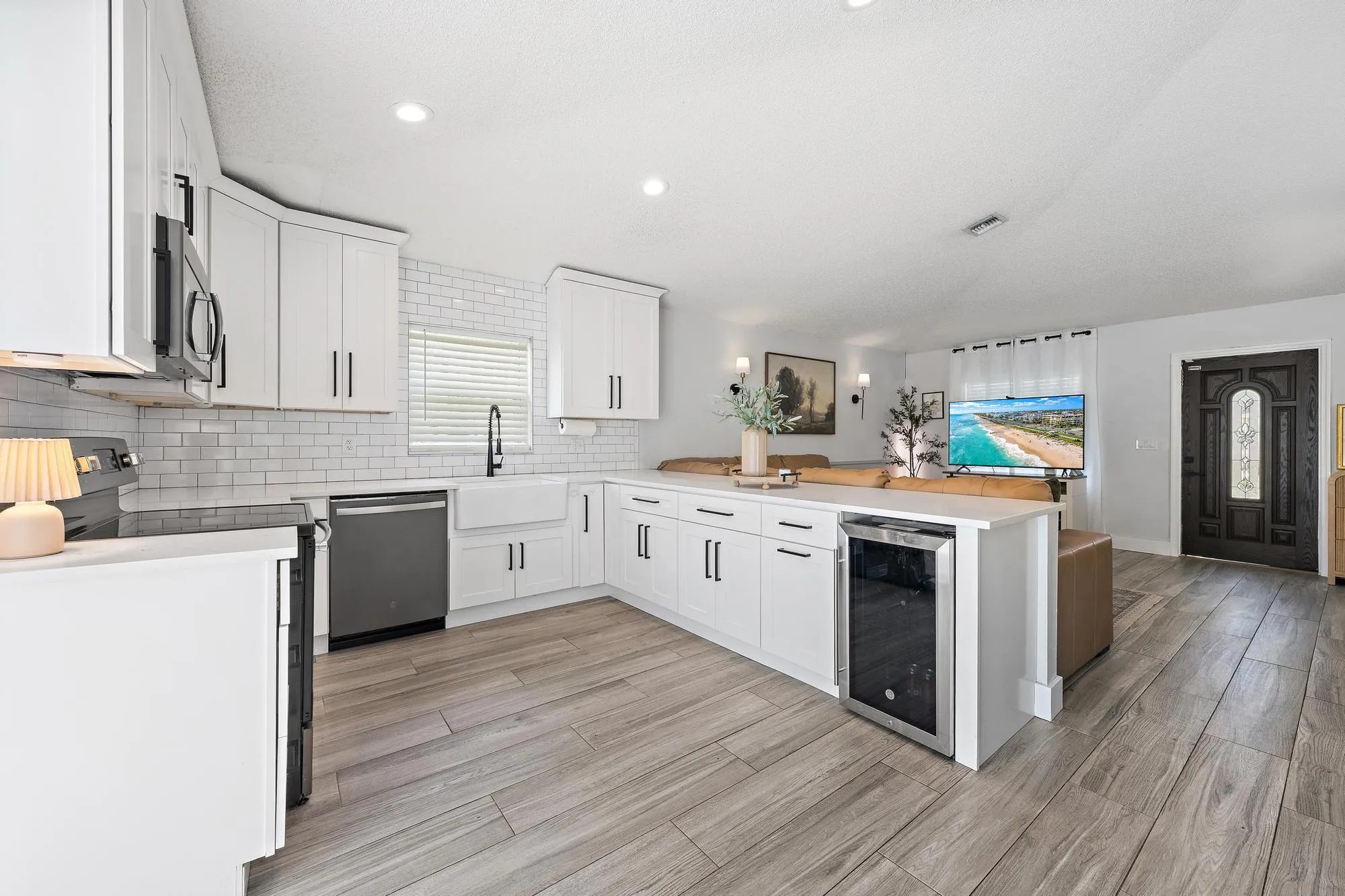 White shaker cabinetry, wood-finish flooring, white subway tile backsplash, farmhouse-style sink, and built-in beverage cooler