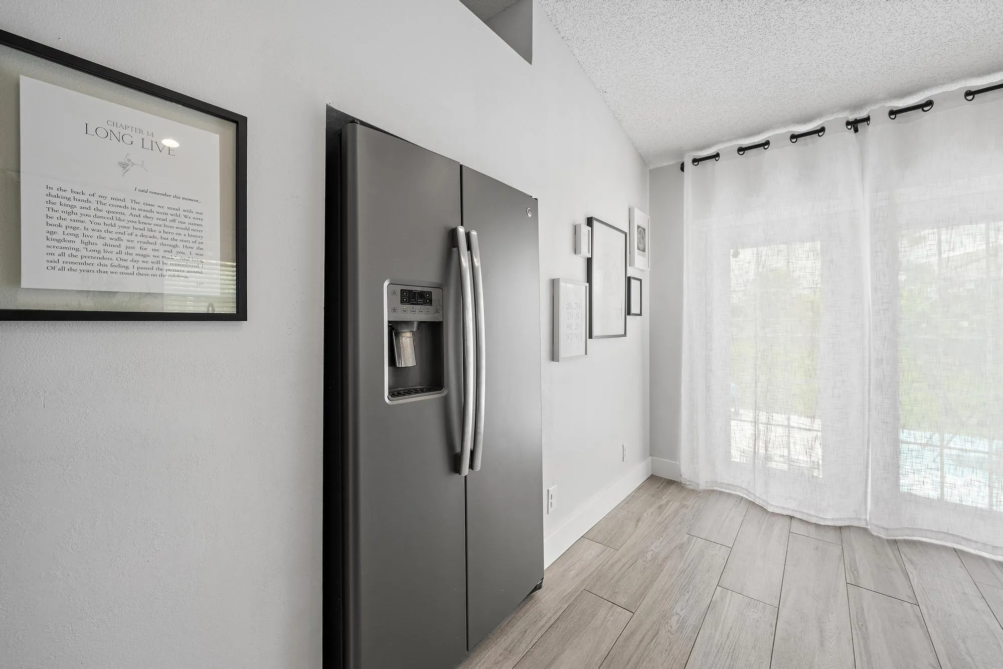 Stainless steel side-by-side refrigerator, vaulted ceiling, wood-finish flooring, and French doors