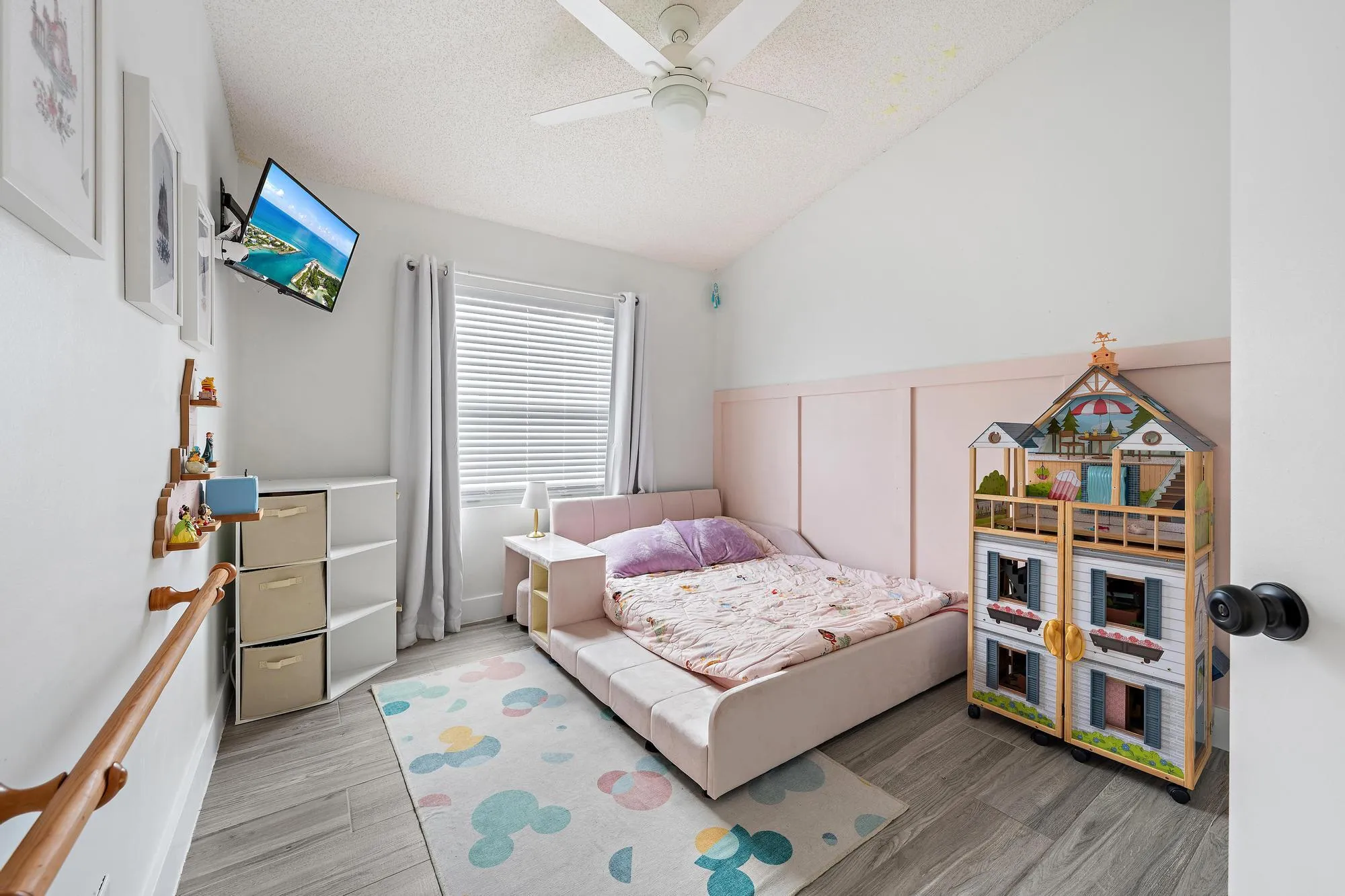 Vaulted ceiling with a ceiling fan, recessed window with blinds, wood-finish flooring, and a decorative wall panel accent