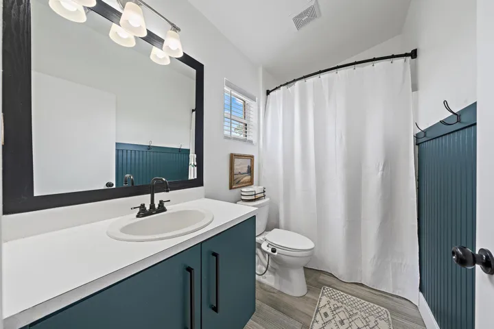 Vanity with white countertop and integrated sink, black hardware, framed mirror, and built-in lighting fixture