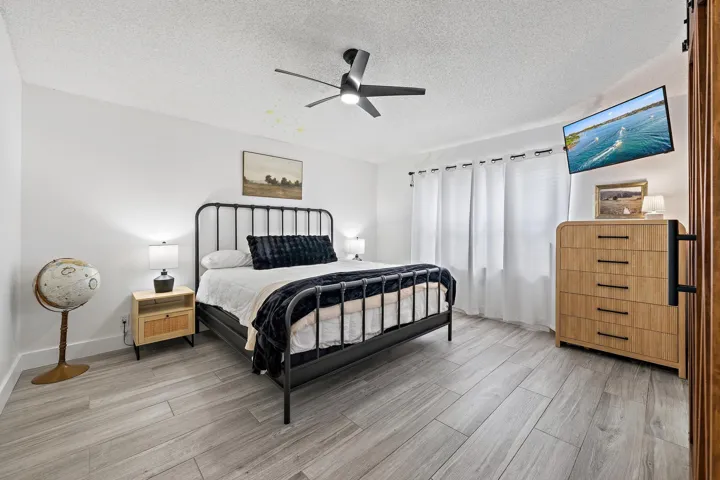 Wood-finish flooring throughout, white walls, and a ceiling fan with light fixture