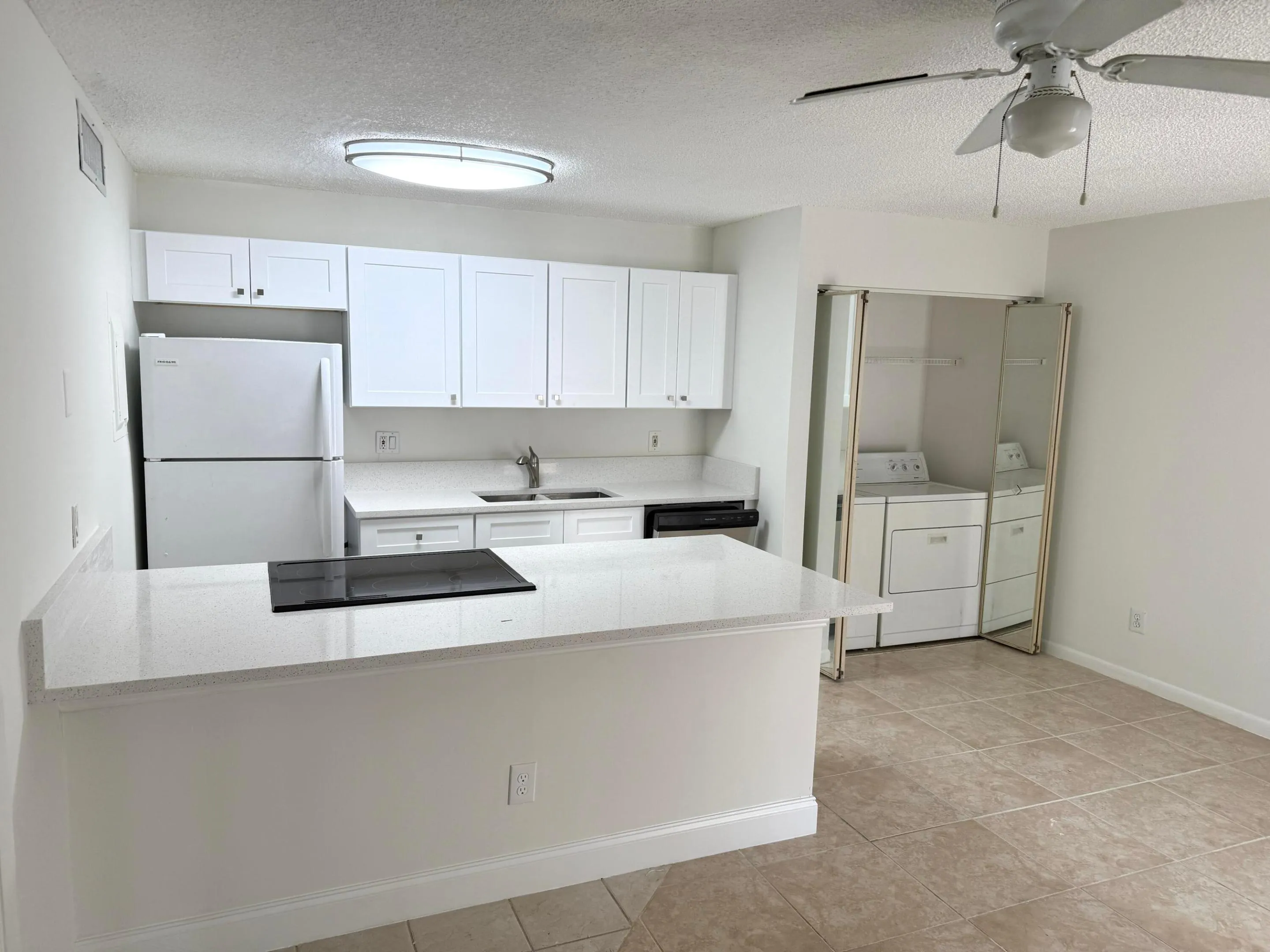 Kitchen featuring white cabinetry, light-toned countertops, a built-in cooktop, and a ceiling fan