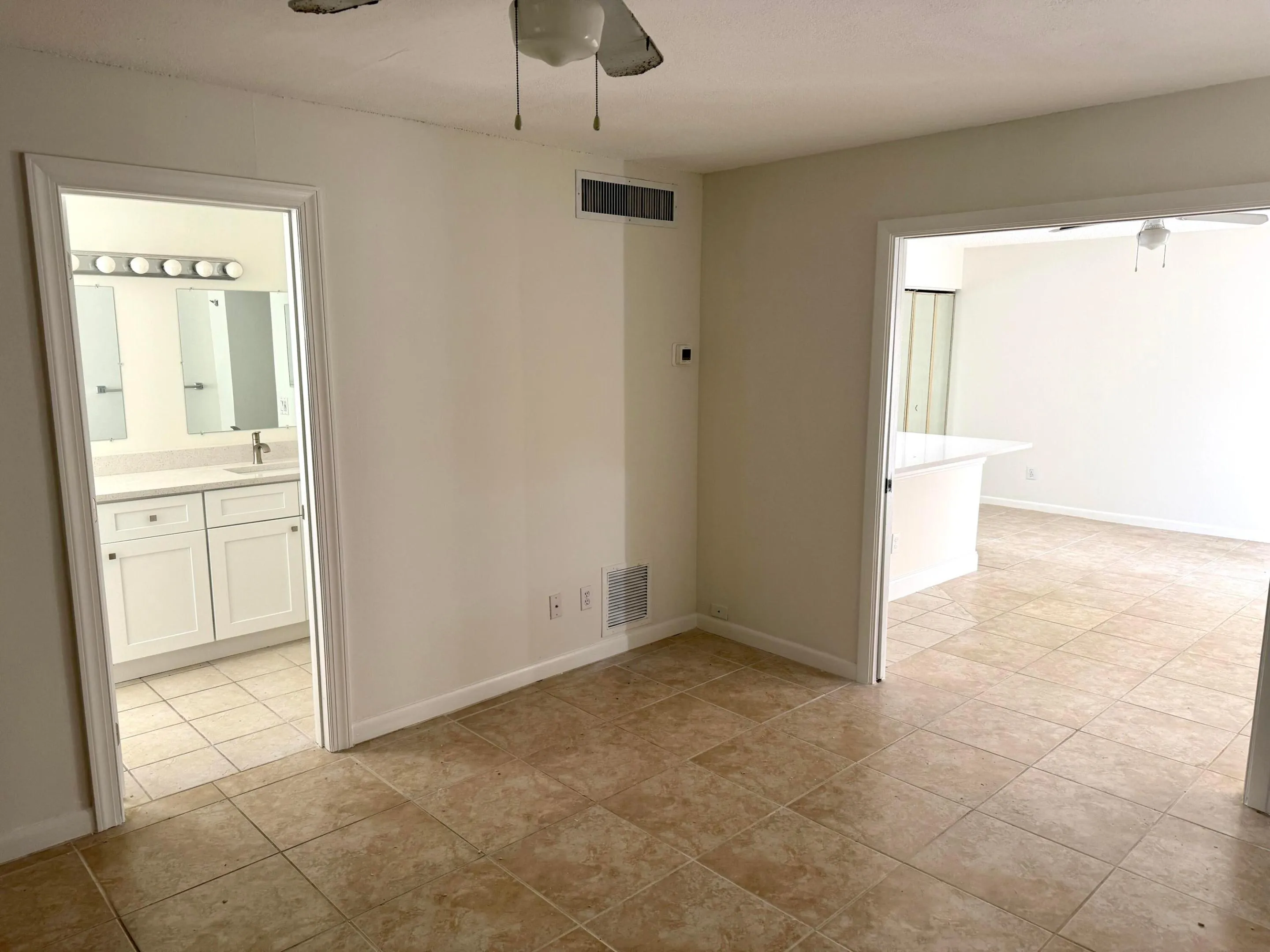 Tile flooring, ceiling fan, white baseboards, and built-in vanity with dual mirrors