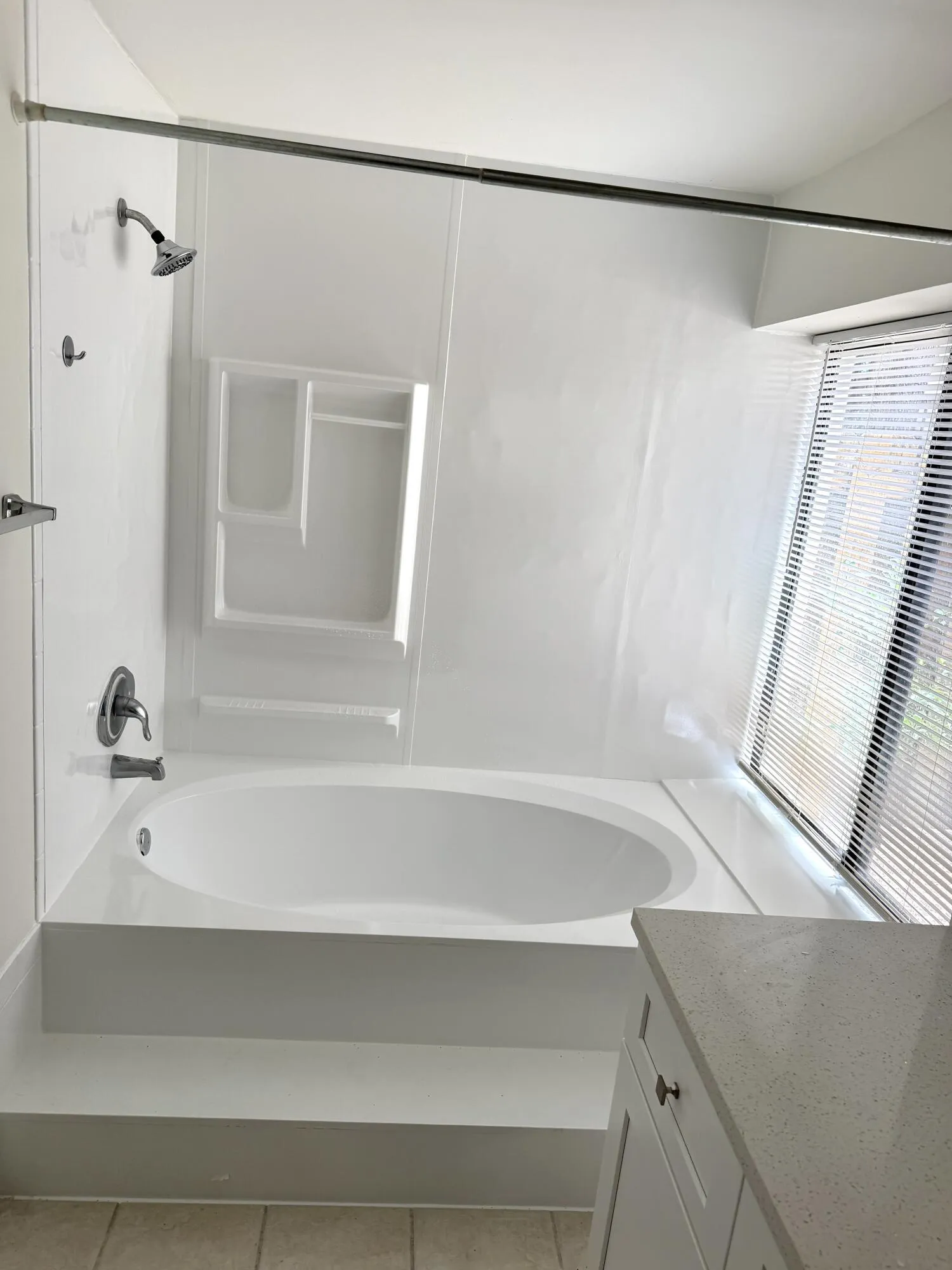 Built-in garden tub with white surround, integrated shower, and adjacent window