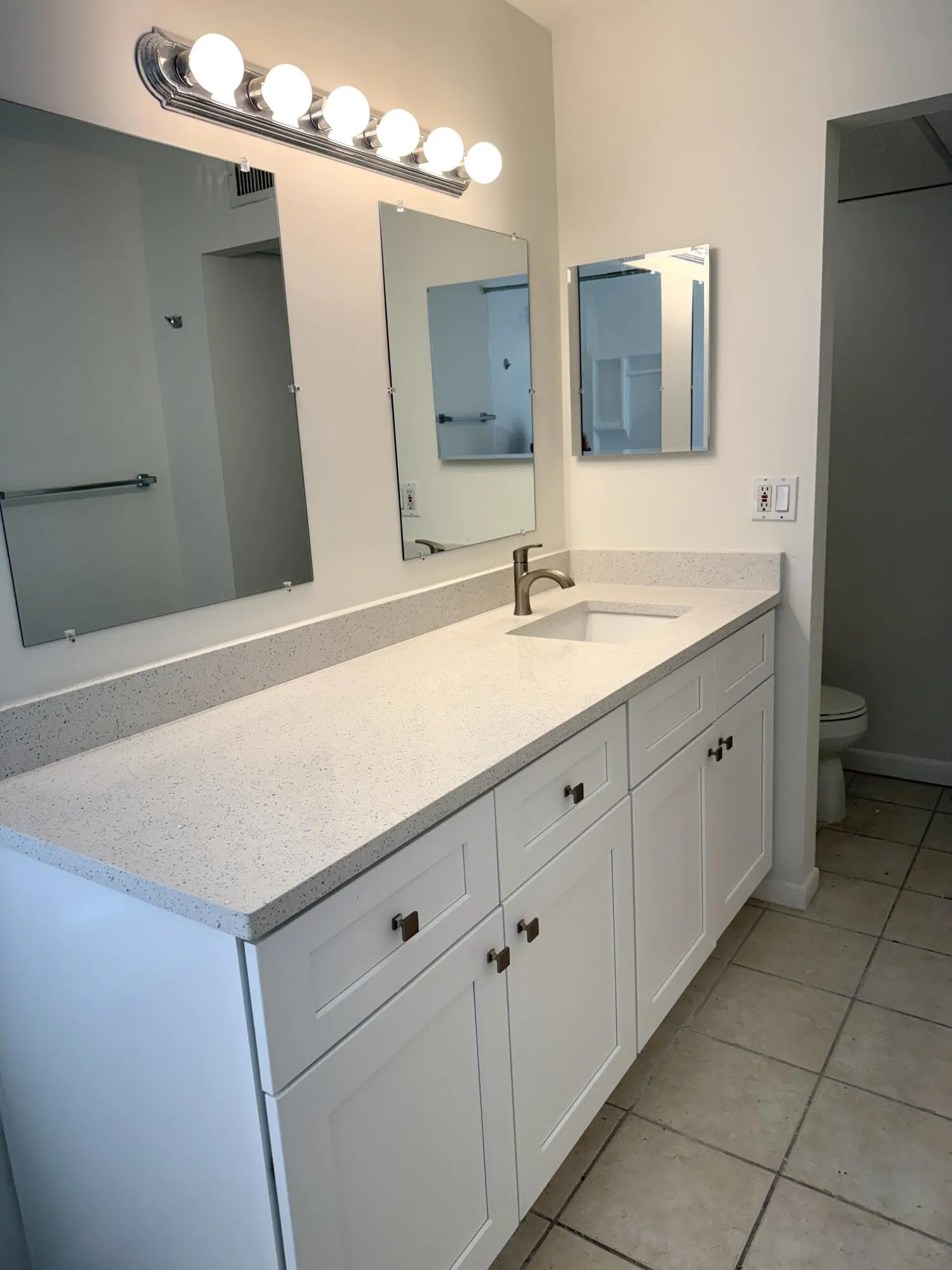 Dual vanity with shaker-style cabinetry, a built-in sink, and a speckled countertop