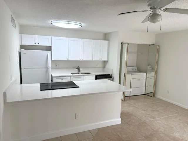 Kitchen featuring white cabinetry, light-toned countertops, a built-in cooktop, and a ceiling fan