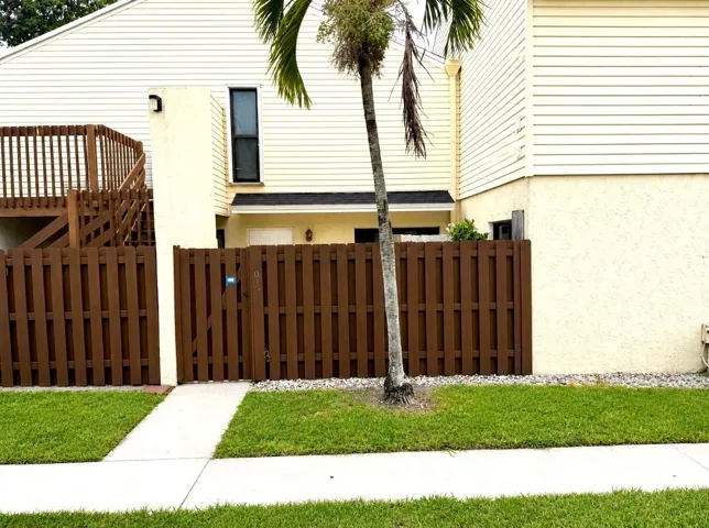 Entryway with a privacy fence and gate, adjacent to a ground-level stucco exterior