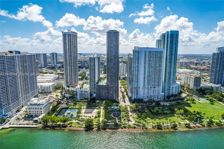 Waterfront high-rise community with multiple residential towers, extensive green spaces, and recreational courts