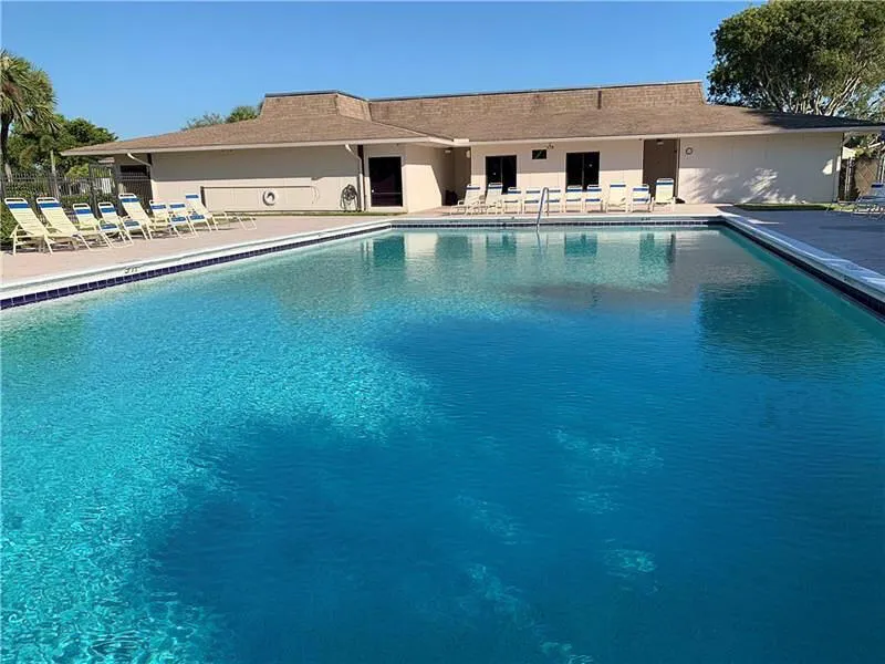 Expansive rectangular swimming pool with a tiled edge and surrounding concrete deck