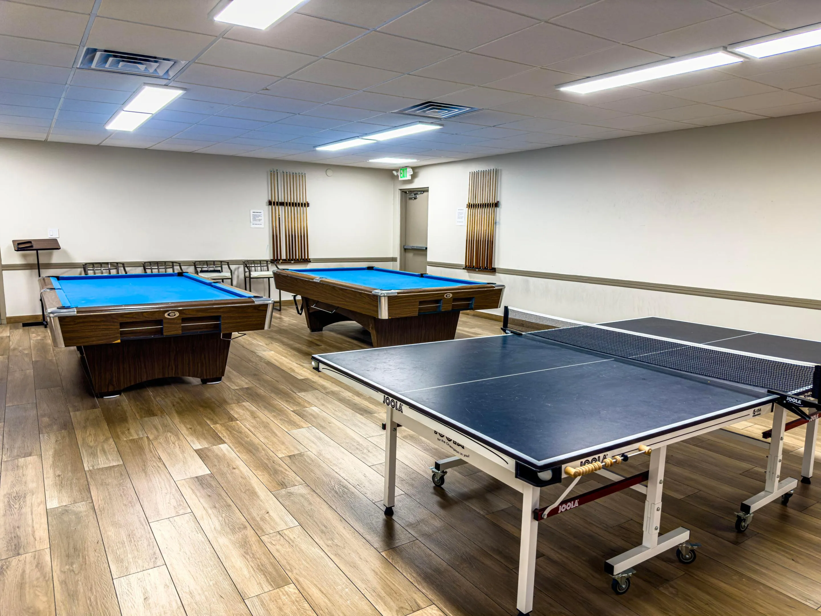 Recreation room featuring two billiards tables with blue felt, a ping-pong table, wood-finish flooring, and recessed ceiling lighting