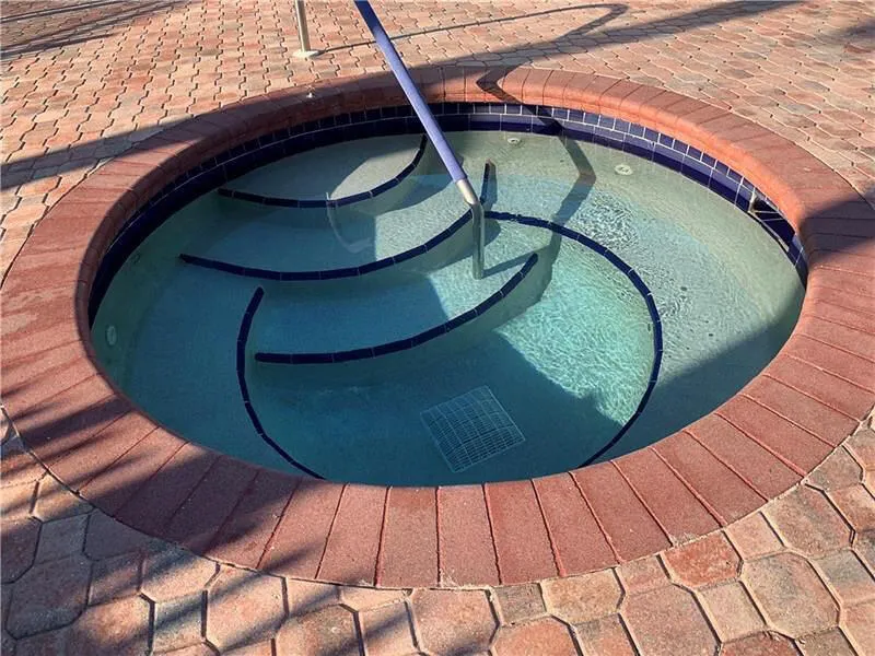 Circular spa with blue mosaic tile and a light-colored interior finish
