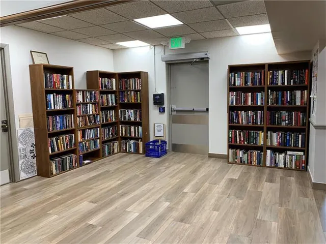 Dedicated library space featuring extensive built-in shelving, wood-finish flooring, recessed lighting, and a neutral color palette