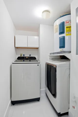 Dedicated utility area with a top-load washing machine, front-load dryer, and overhead cabinetry