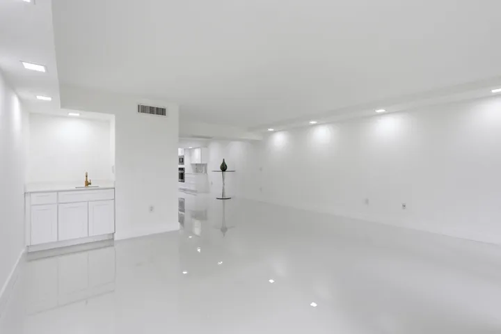 Expansive room featuring glossy tile flooring, recessed lighting, and a built-in wet bar with white cabinetry and a light-toned countertop