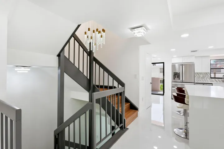Modern kitchen featuring stainless steel appliances, white cabinetry, and beatifyl staircase