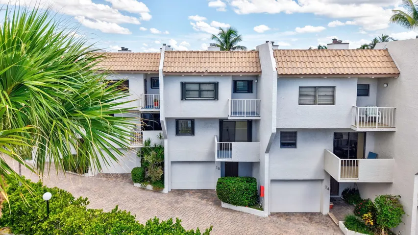Multi-level exterior with tile roofing, private balconies, integrated garages, and mature landscaping