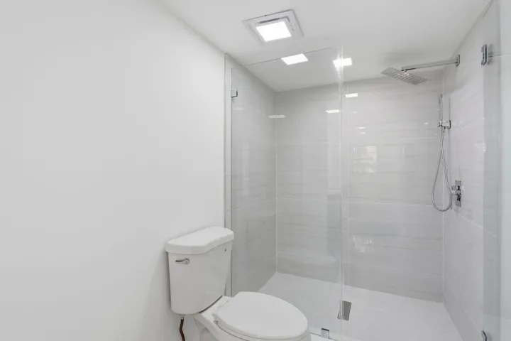 Walk-in shower with clear glass enclosure, tiled walls, and a rainfall showerhead