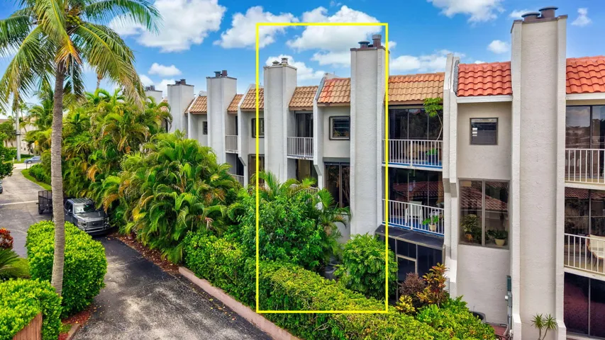 Stucco exterior with multiple balconies, tile roofing, and mature landscaping