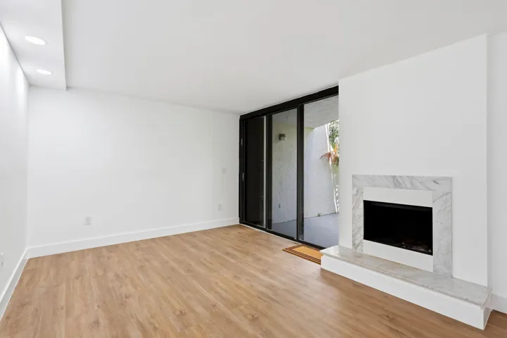 Wood-finish flooring, recessed lighting, and a white fireplace surround with a stone hearth
