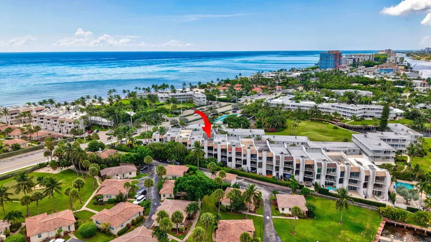 Coastal condominium community with multiple buildings, lush landscaping, and integrated swimming pool