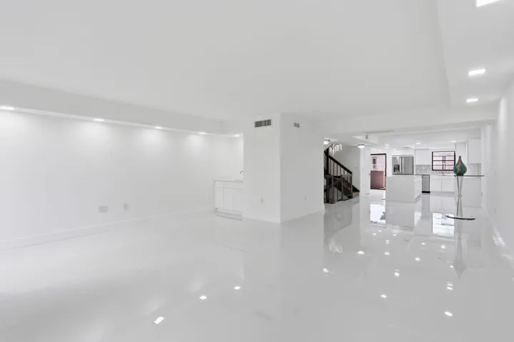 Open-concept living space featuring high-gloss tile flooring, recessed lighting, and a white cabinet with a sink