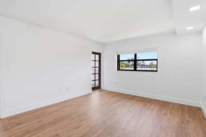 Wood-finish flooring, white painted walls, recessed lighting, French-style door, and a horizontal window with blinds