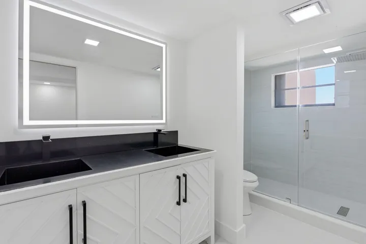 Dual vanity with integrated sinks, black countertop, and white cabinetry