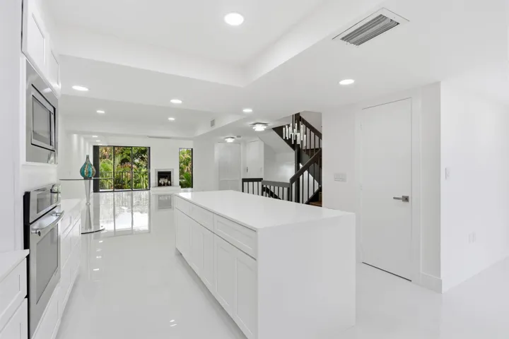Open-concept kitchen with a large island, integrated stainless steel appliances, recessed ceiling lighting, and hard-surface flooring
