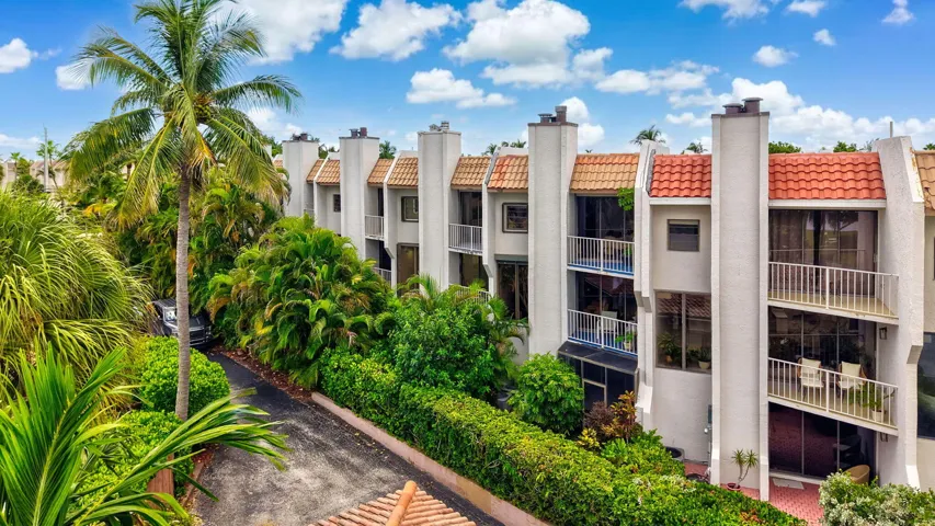 Multi-level townhome featuring white stucco exterior, terracotta roof tiles, and multiple balconies with white railings