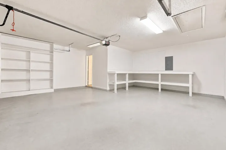 Finished garage interior with built-in shelving, a workbench, and overhead lighting