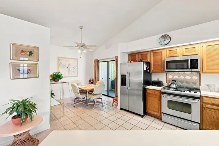 Kitchen and dining area featuring tile flooring, wood-finish cabinetry, stainless steel appliances, and a ceiling fan