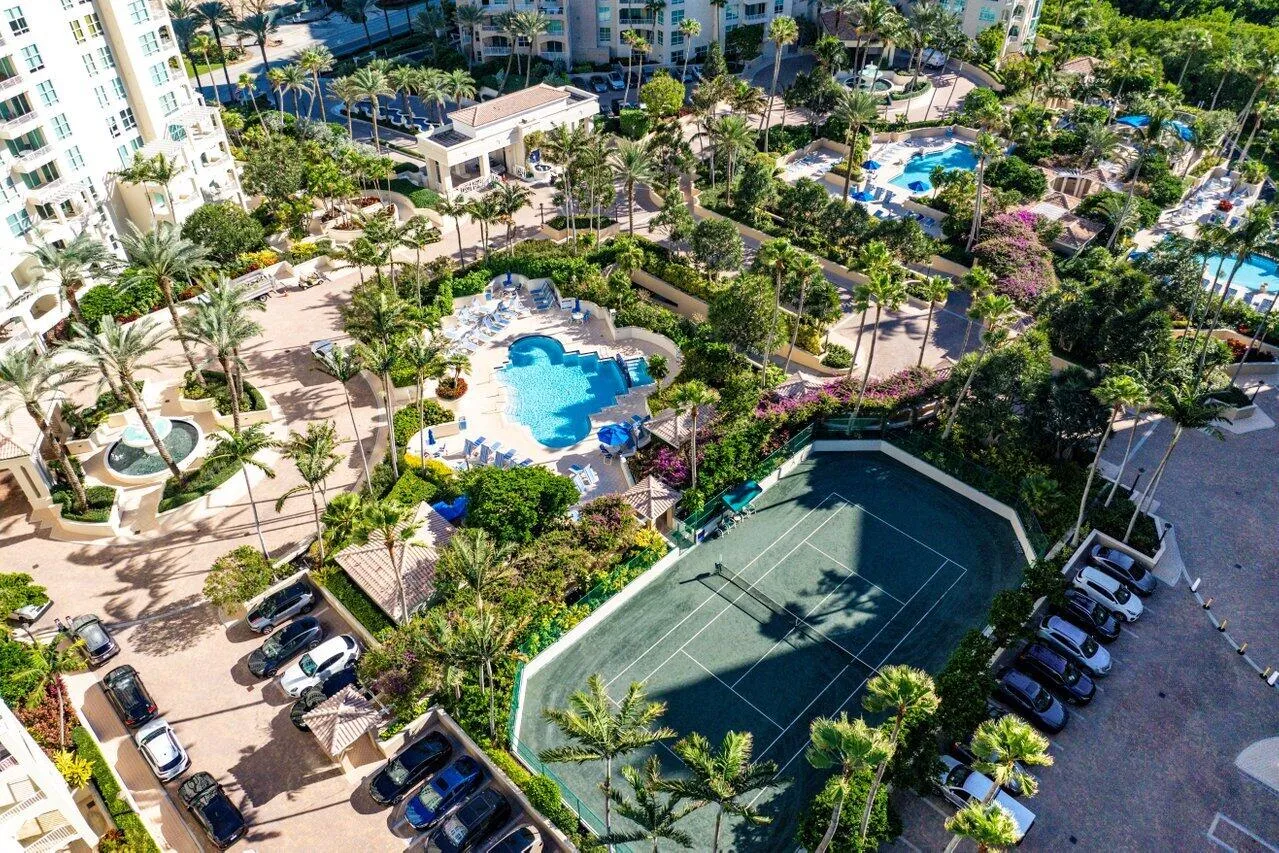 Expansive grounds featuring multiple swimming pools, a tennis court, and lush landscaping