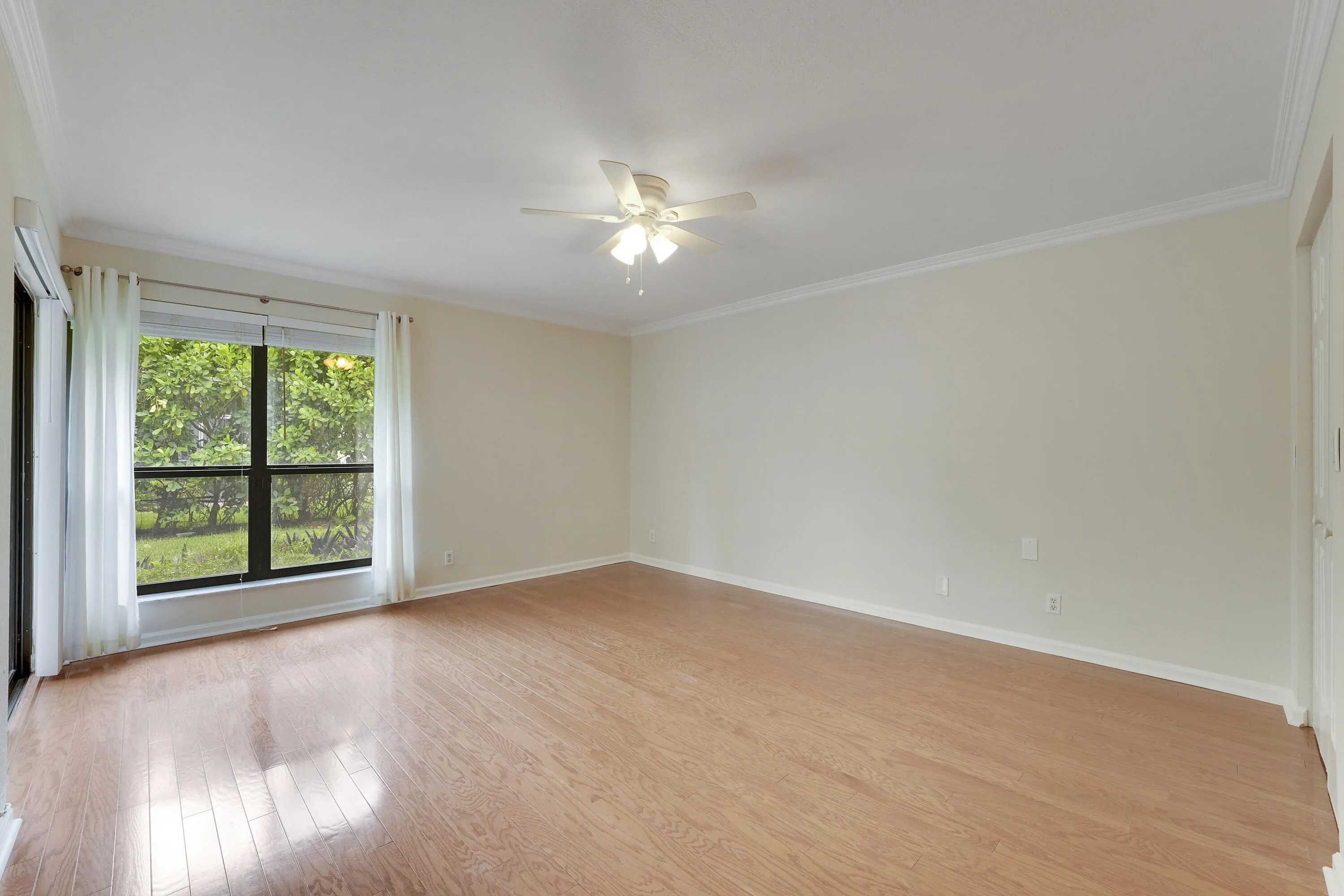 Primary bedroom with wood flooring and crown molding