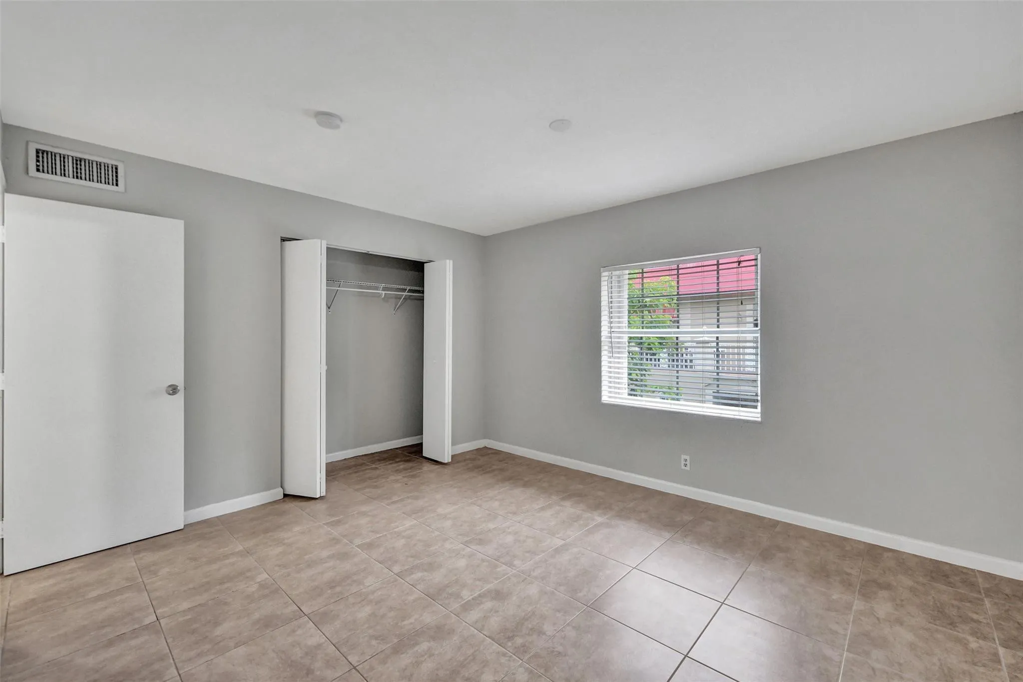 Spacious bedroom featuring tile flooring, a walk-in closet with shelving, and an additional reach-in closet