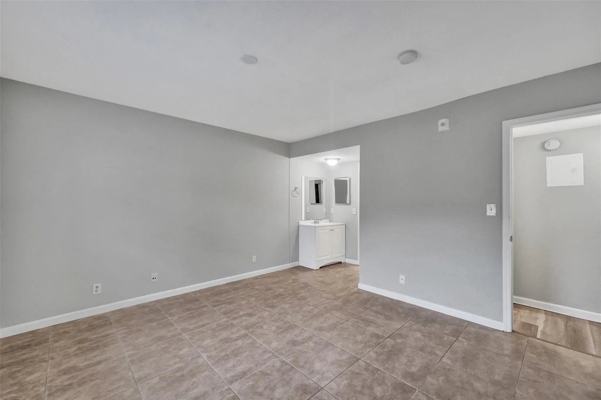 Spacious room featuring neutral gray walls, recessed ceiling lighting, and wood-finish flooring throughout