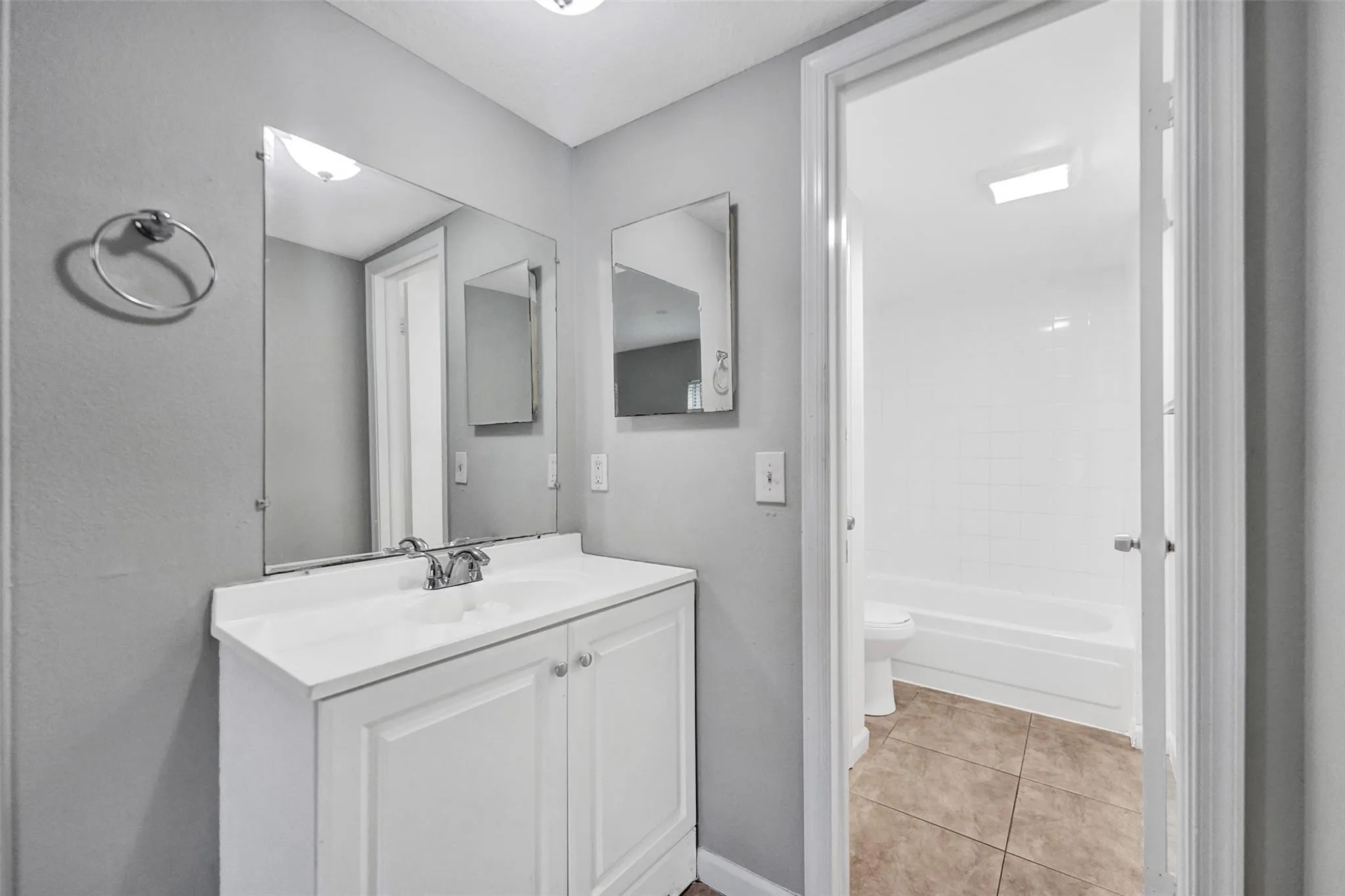 Modern bathroom vanity featuring a white cabinetry base, rectangular sink with chrome faucet, and large framed mirror