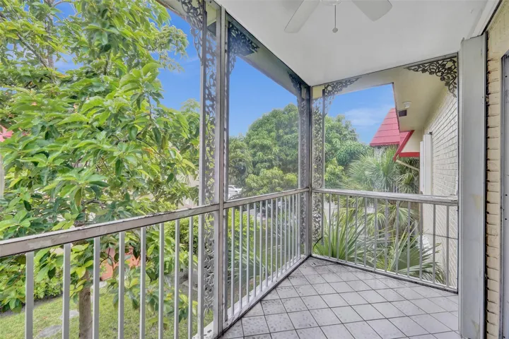 Screened patio featuring a ceiling fan, white tile flooring, and decorative metalwork