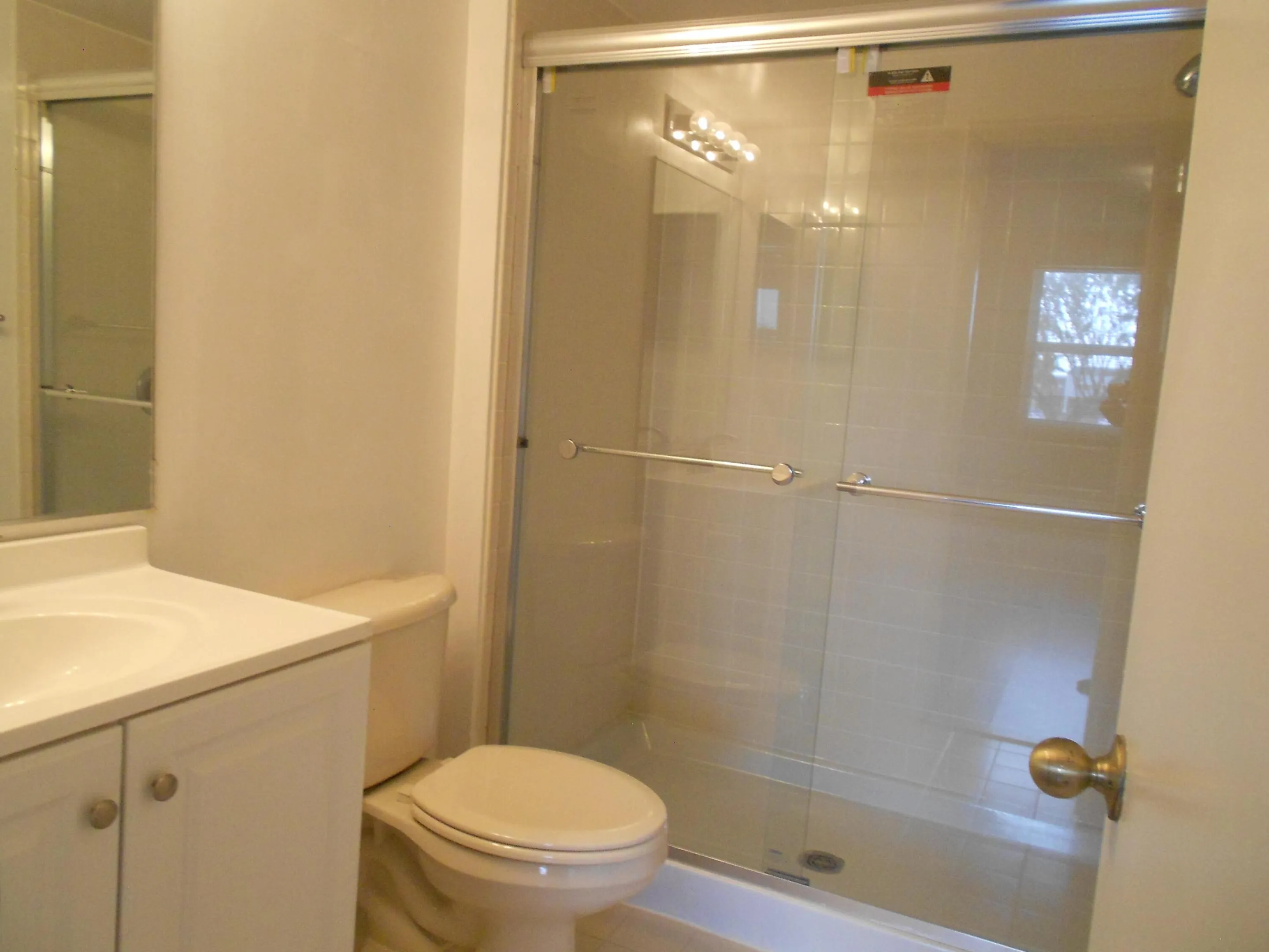 Spa-inspired bathroom featuring a frameless glass shower enclosure with brushed nickel hardware, white vanity cabinetry with dual sinks, and neutral tile finishes throughout