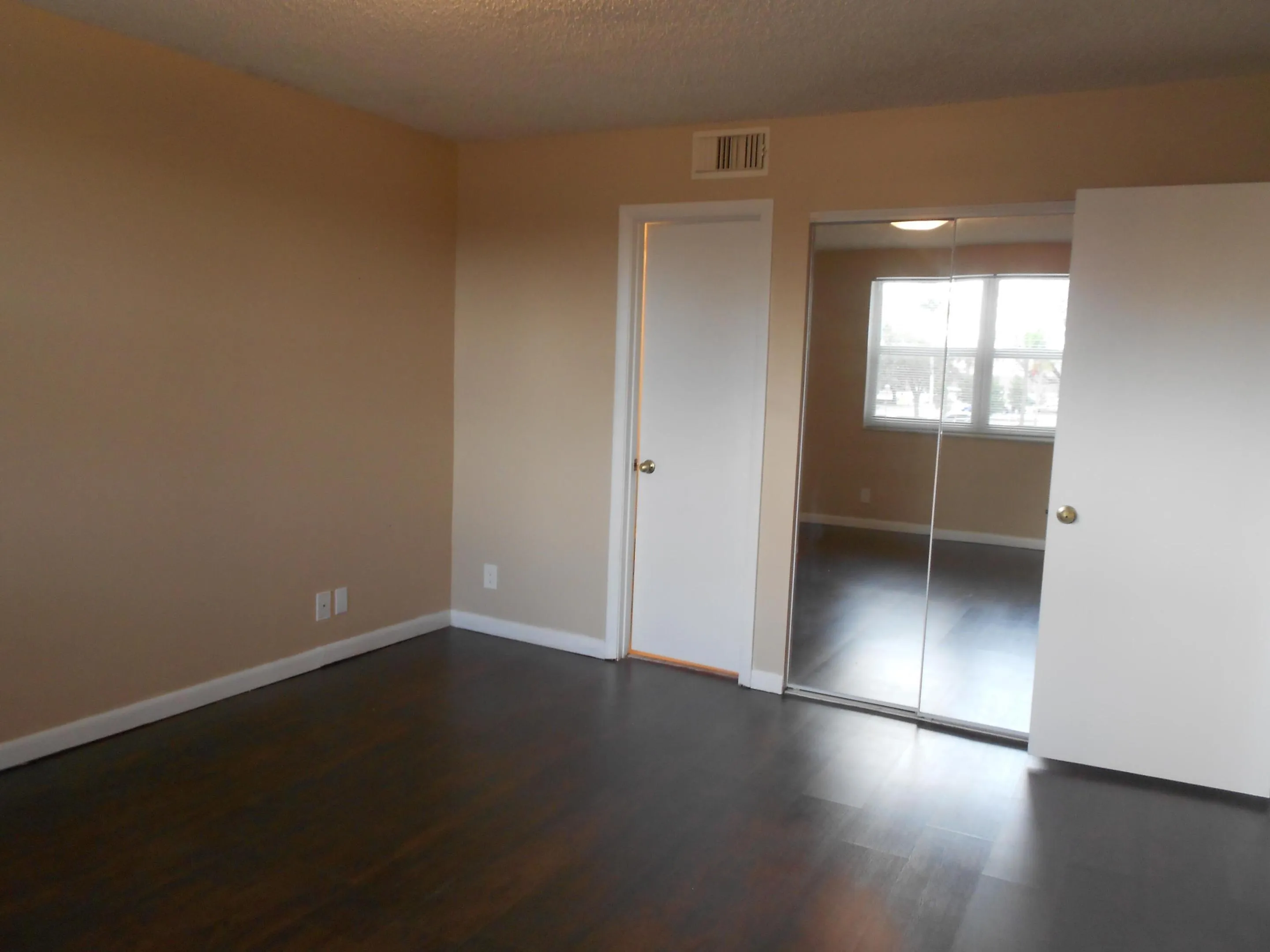 Wood-finish flooring, neutral-toned walls, and mirrored closet doors