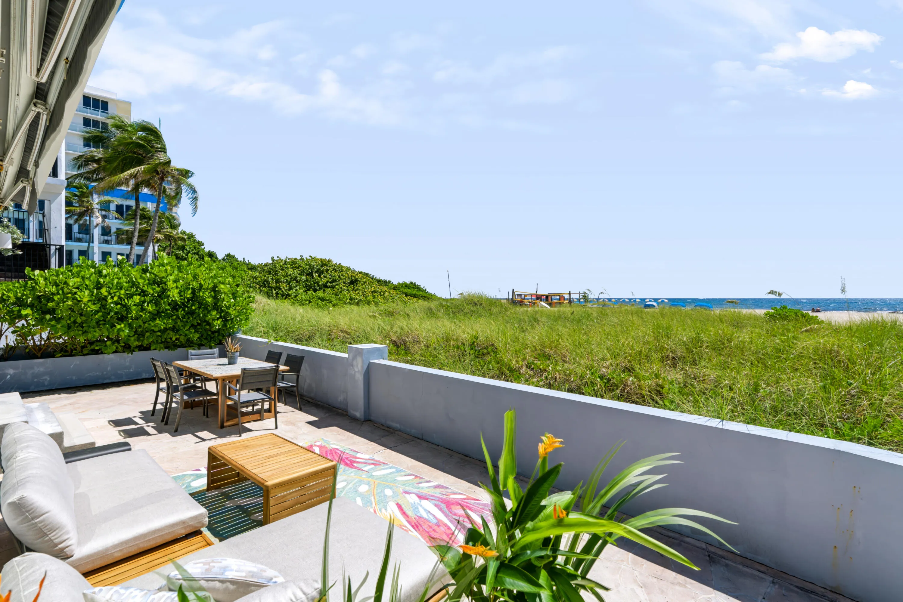 Spacious outdoor patio with concrete flooring, low perimeter wall, and established perimeter plantings