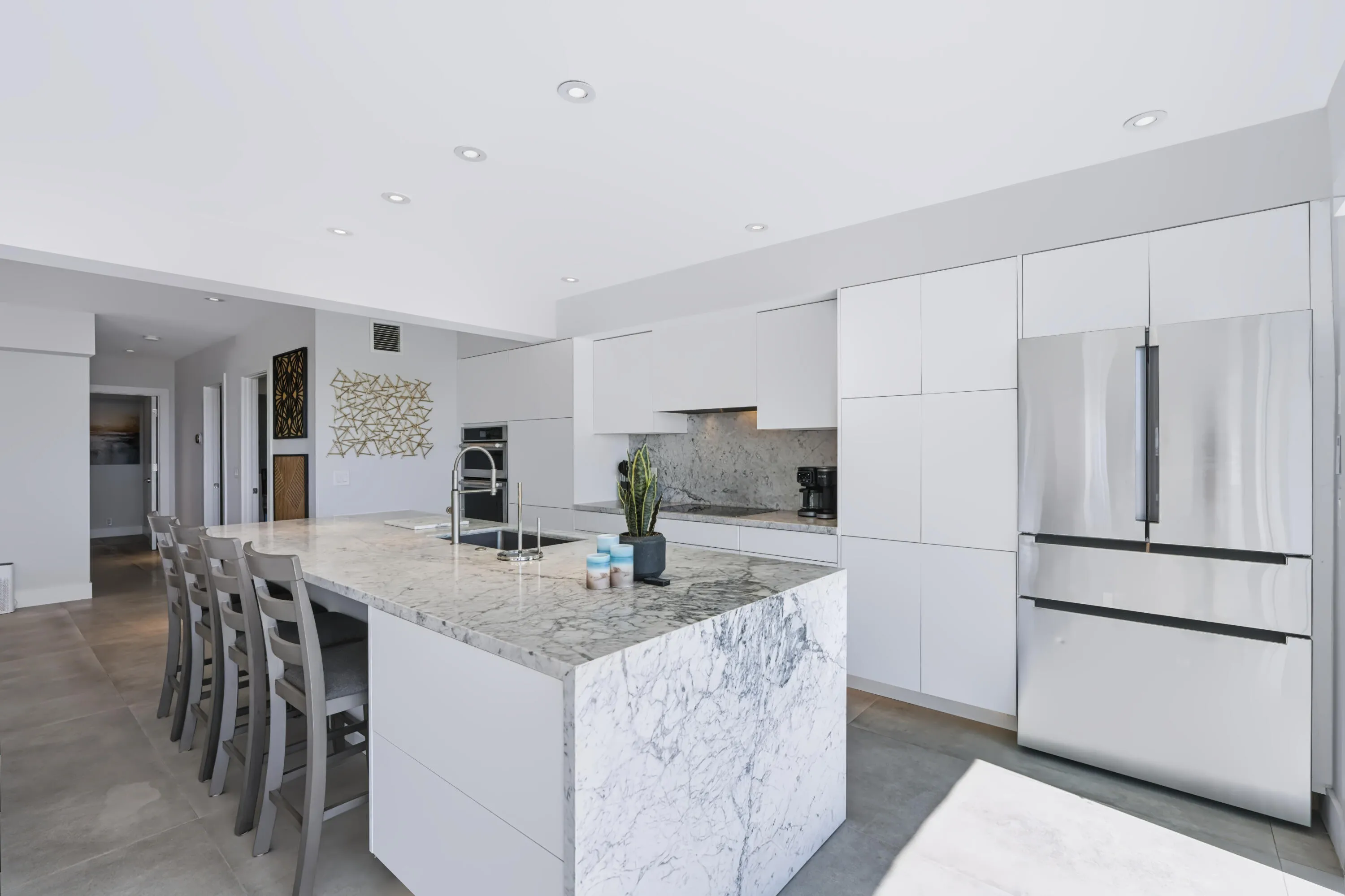 Kitchen featuring white flat-panel cabinetry, a large kitchen island with a stone countertop, a stainless steel refrigerator, and recessed lighting