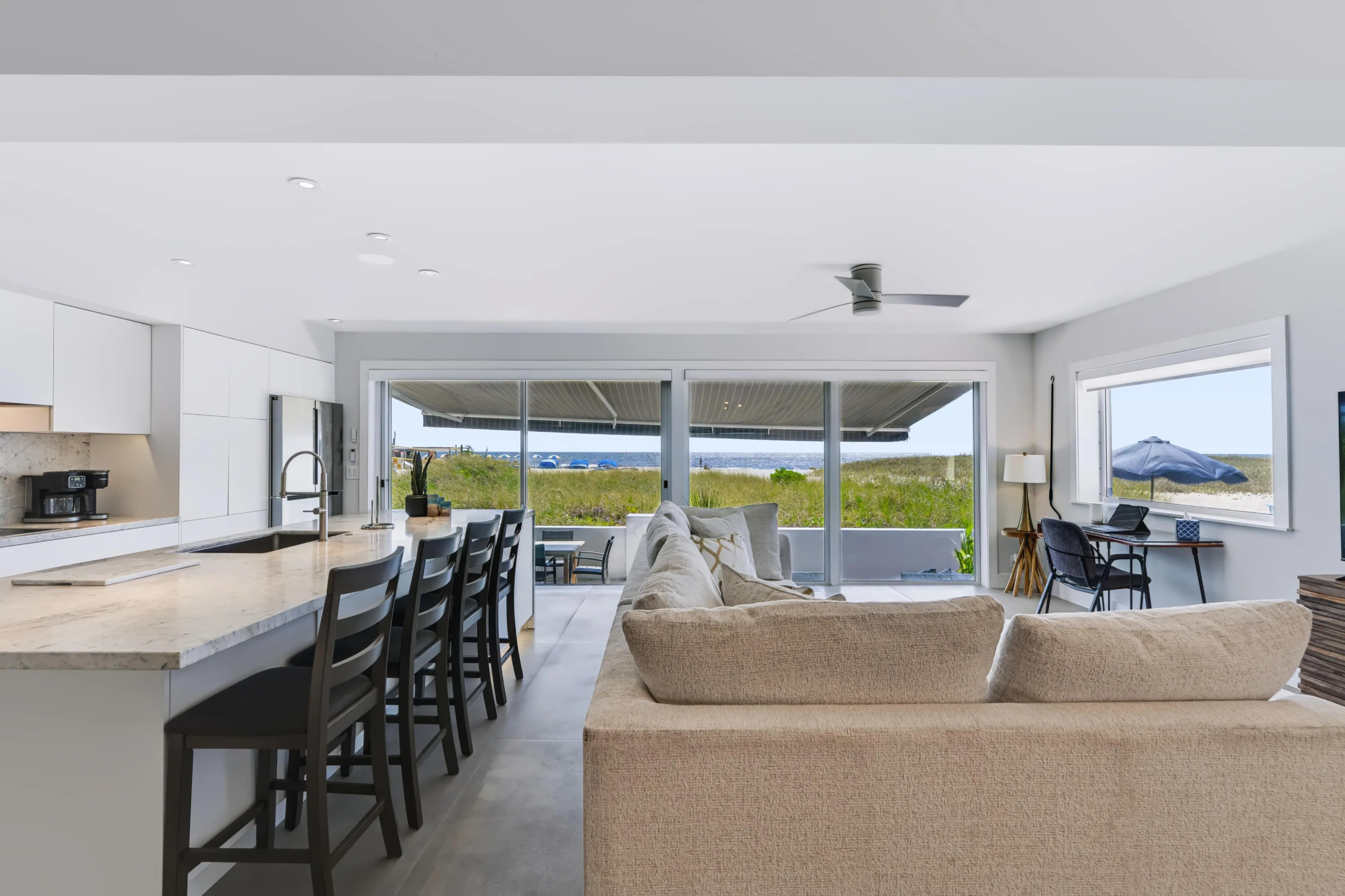 Open-concept living area featuring a kitchen island with seating, integrated appliances, and sliding glass doors leading to a terrace