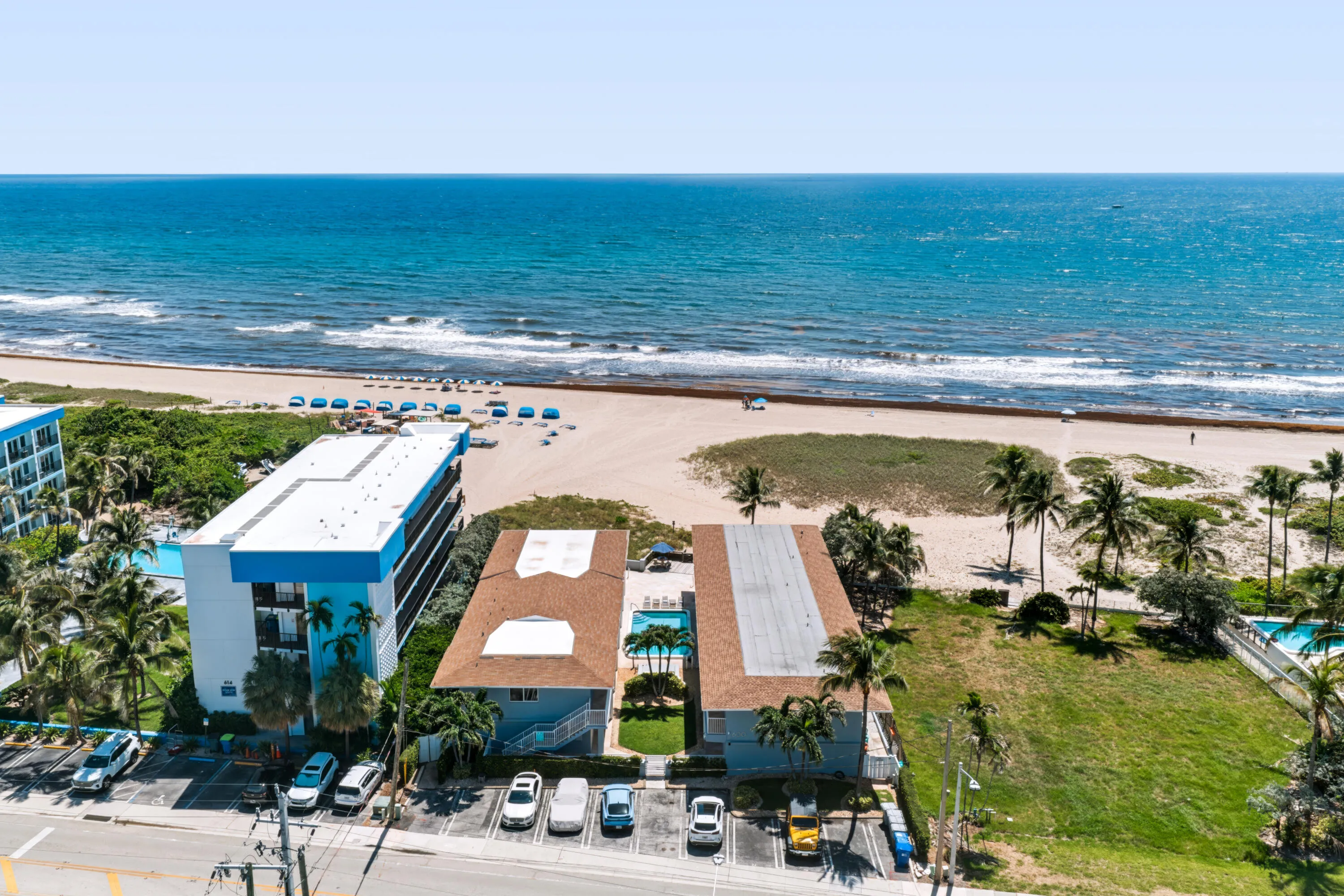 Oceanfront property featuring a sandy beach, mature palm trees, and an outdoor swimming pool
