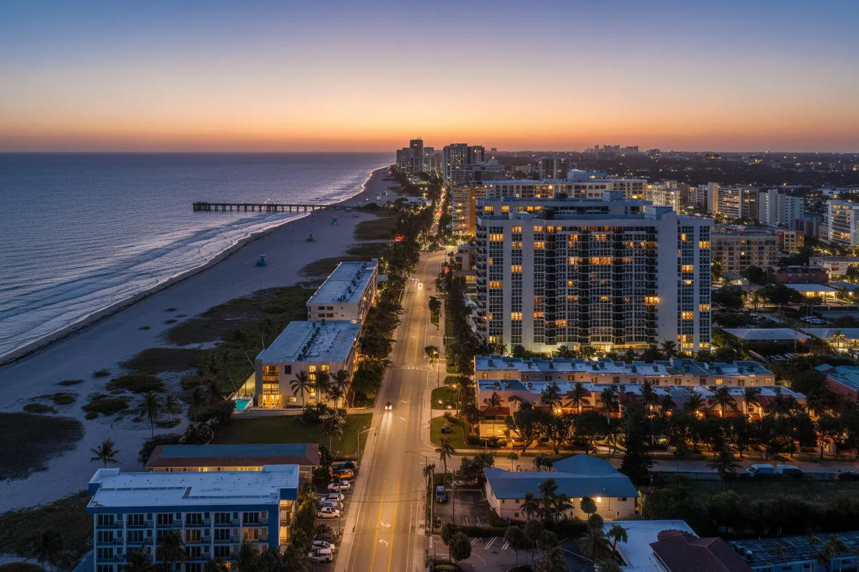Oceanfront community with a prominent pier, a long sandy beach, and a high-rise building with multiple balconies
