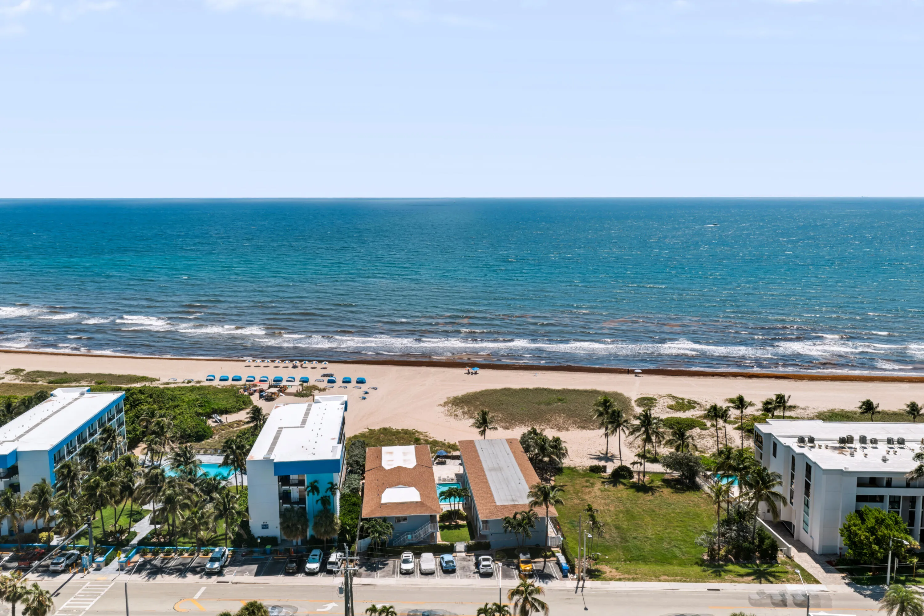 Expansive oceanfront with beach access, featuring a swimming pool, palm trees, and direct proximity to the shoreline