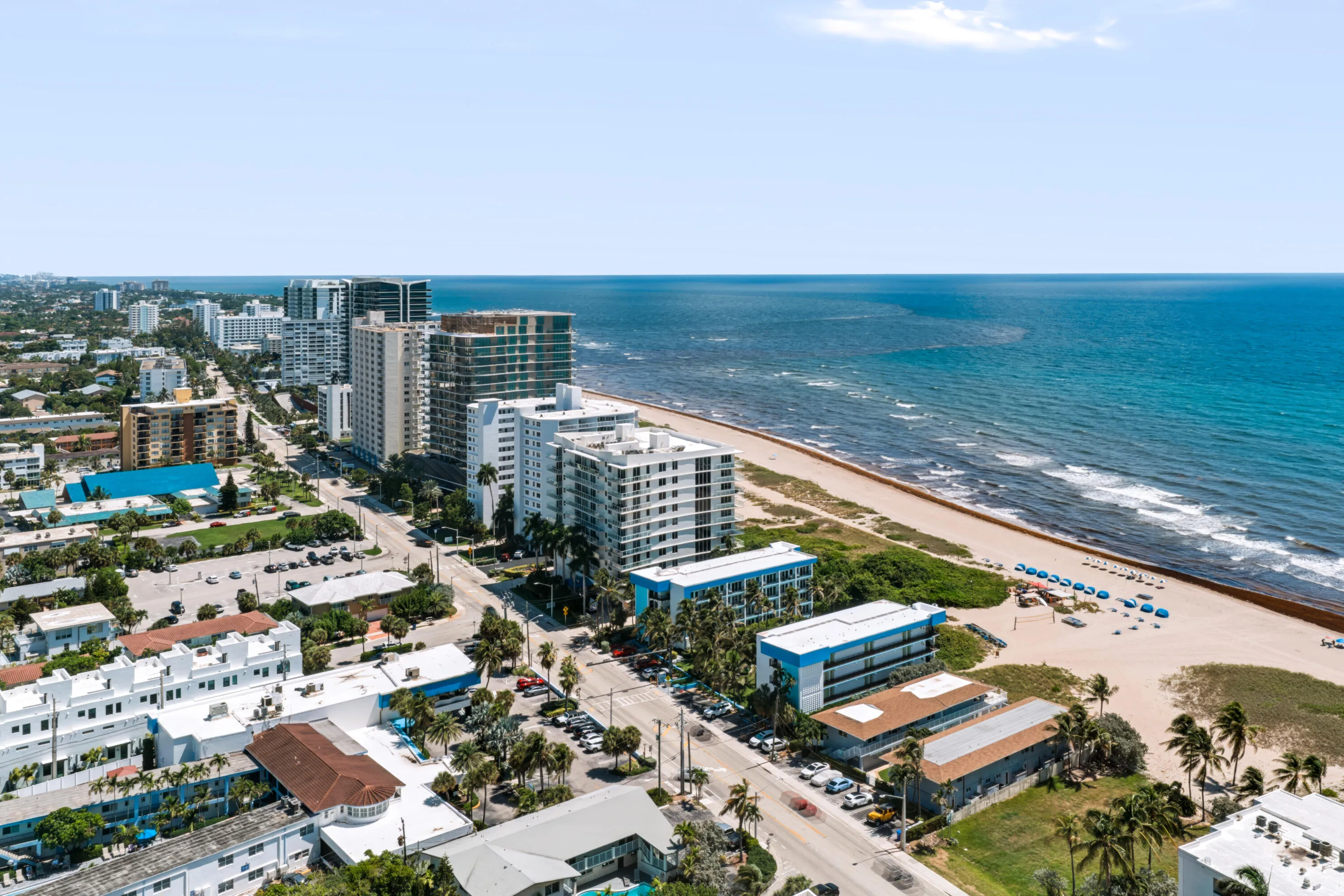 Coastal urban setting with a wide sandy beach, clear blue ocean, and high-rise buildings
