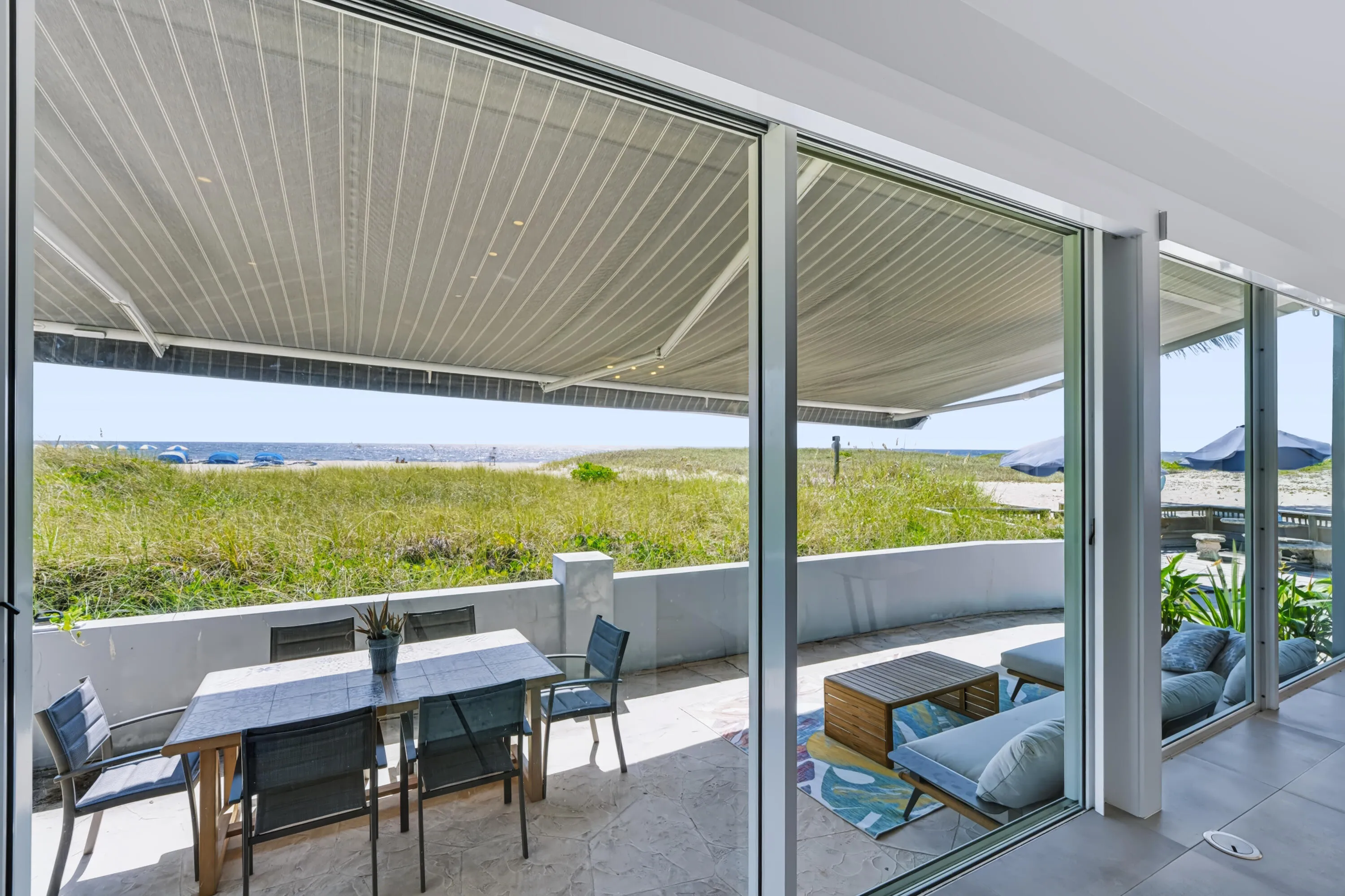 Expansive outdoor patio with privacy wall, retractable awning, and direct beach​​‌​​​​‌​​‌‌​‌‌​​​‌‌​‌​‌​‌​​​‌​​ access