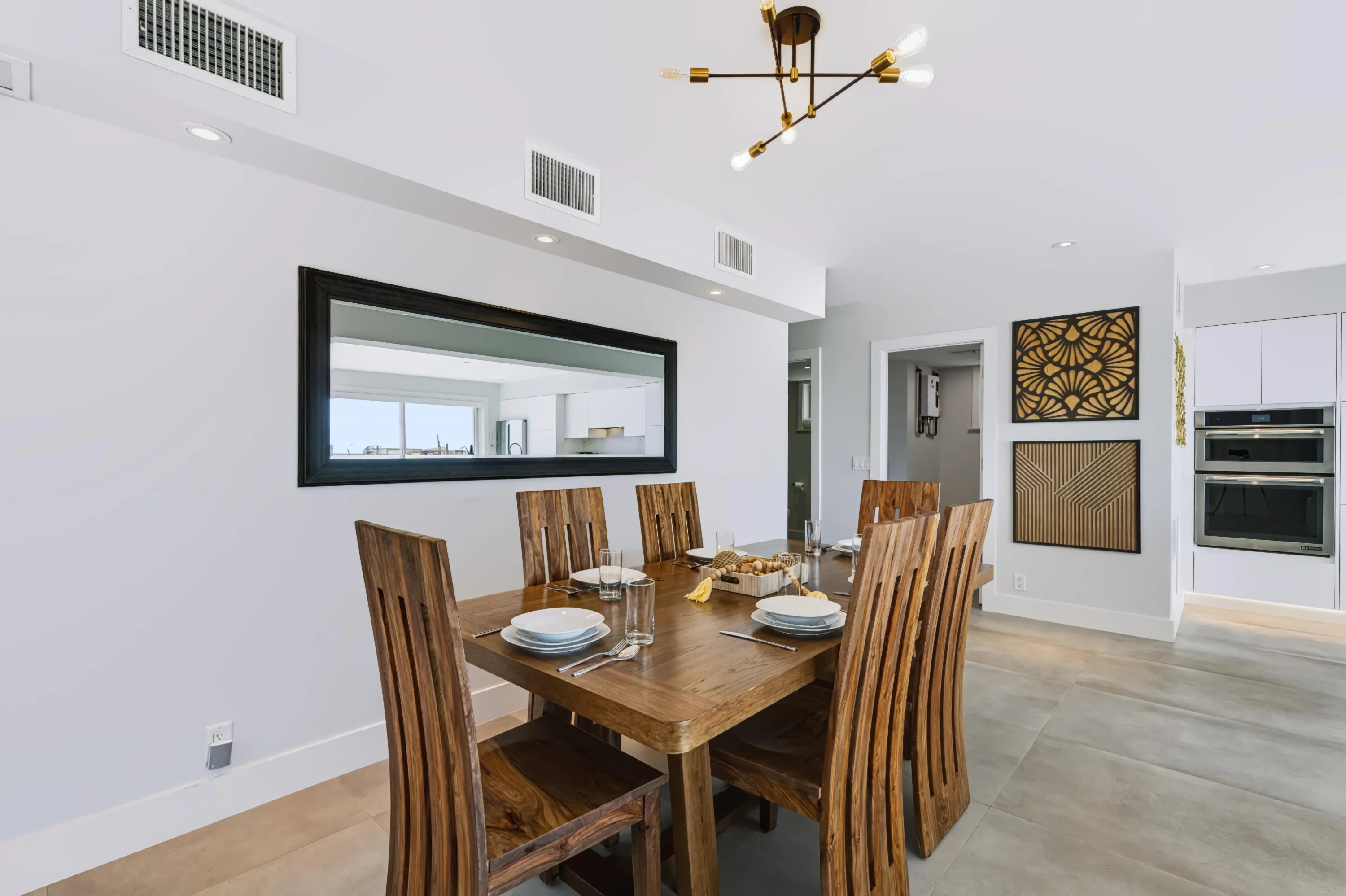 Hardwood dining table with matching chairs, recessed lighting, and a modern chandelier