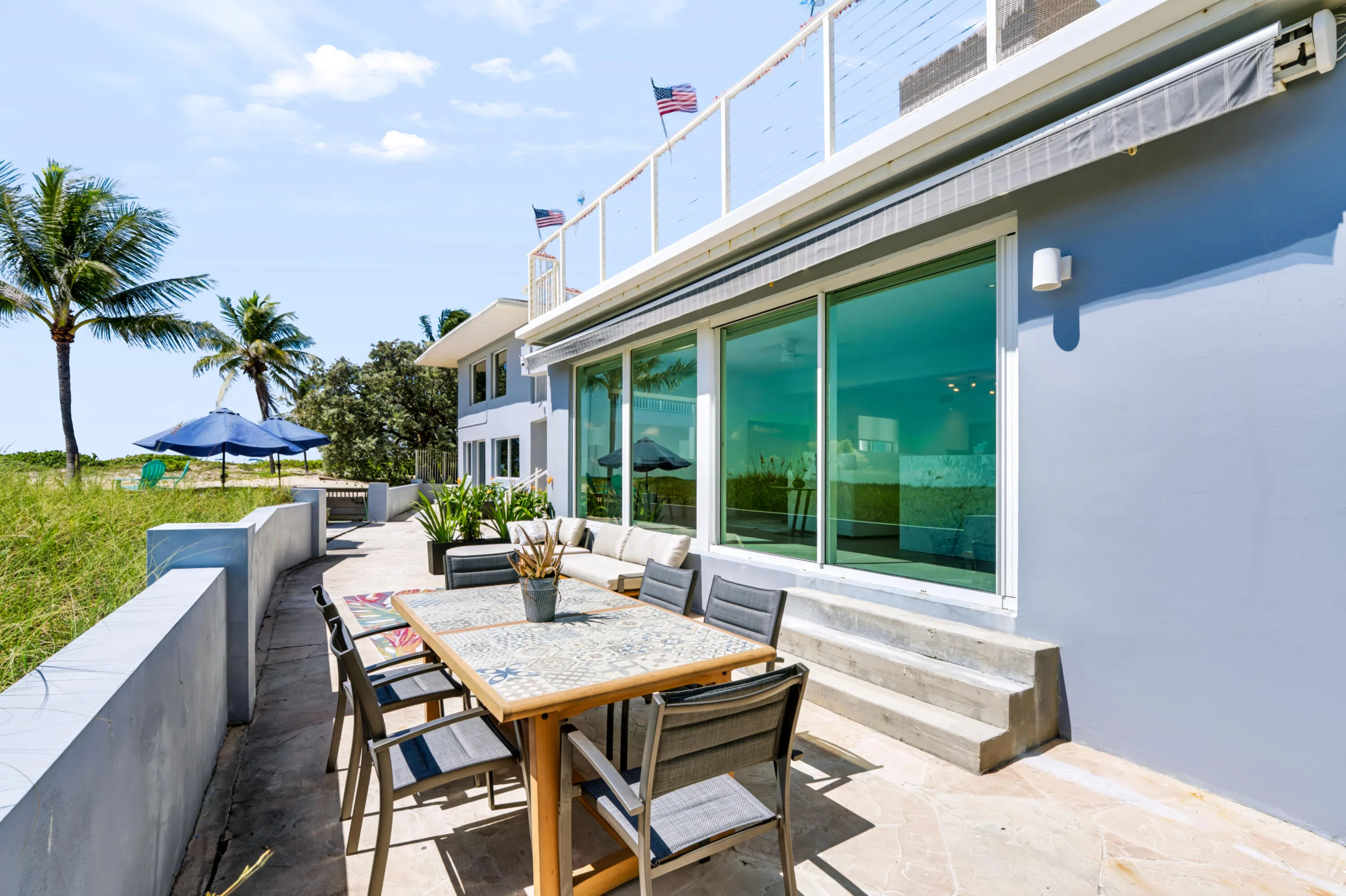 Spacious outdoor patio with tiled flooring, concrete retaining wall, and large sliding glass doors