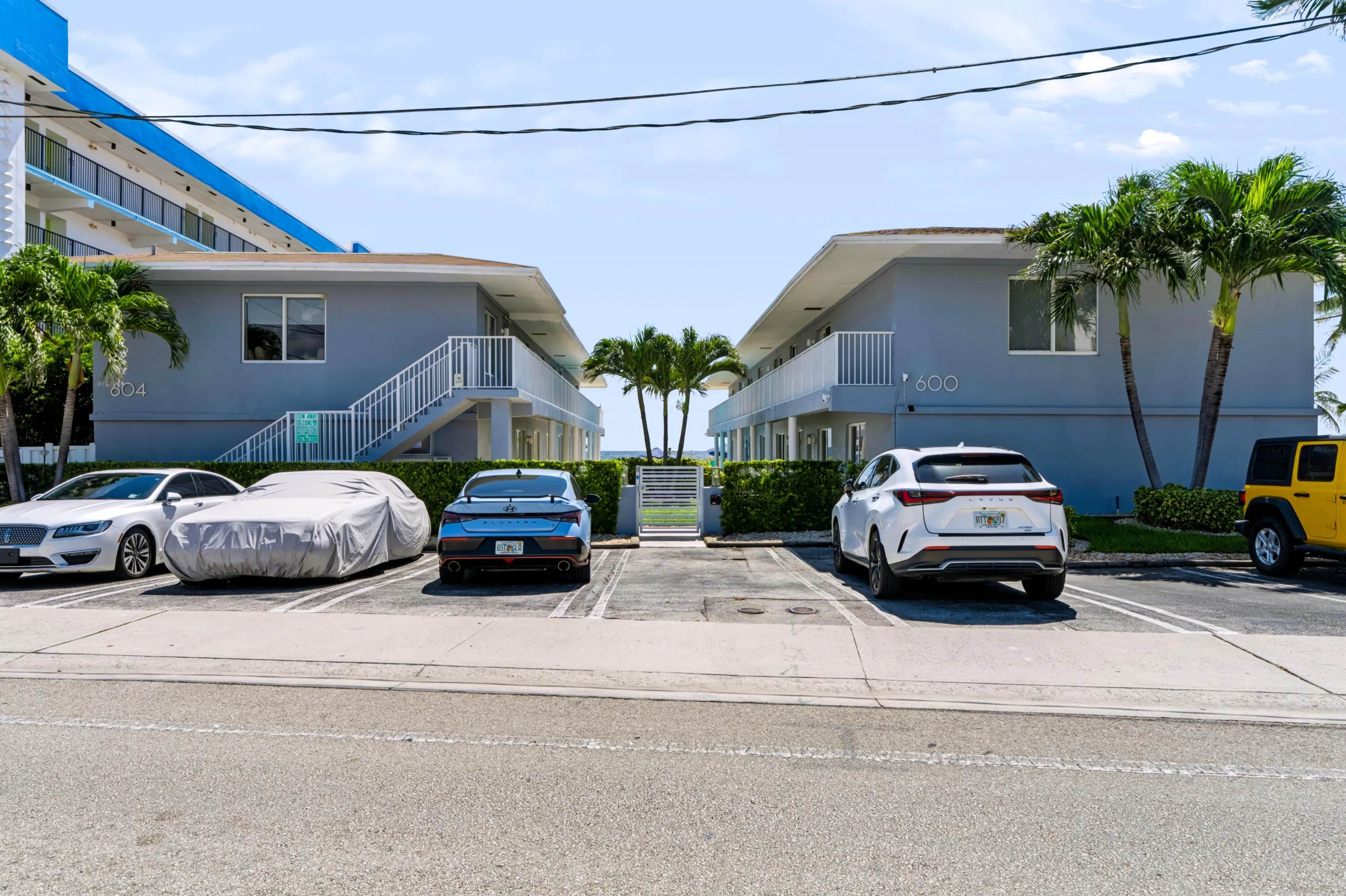 Two-story residences with exterior stair access, white railings, and mature palm trees